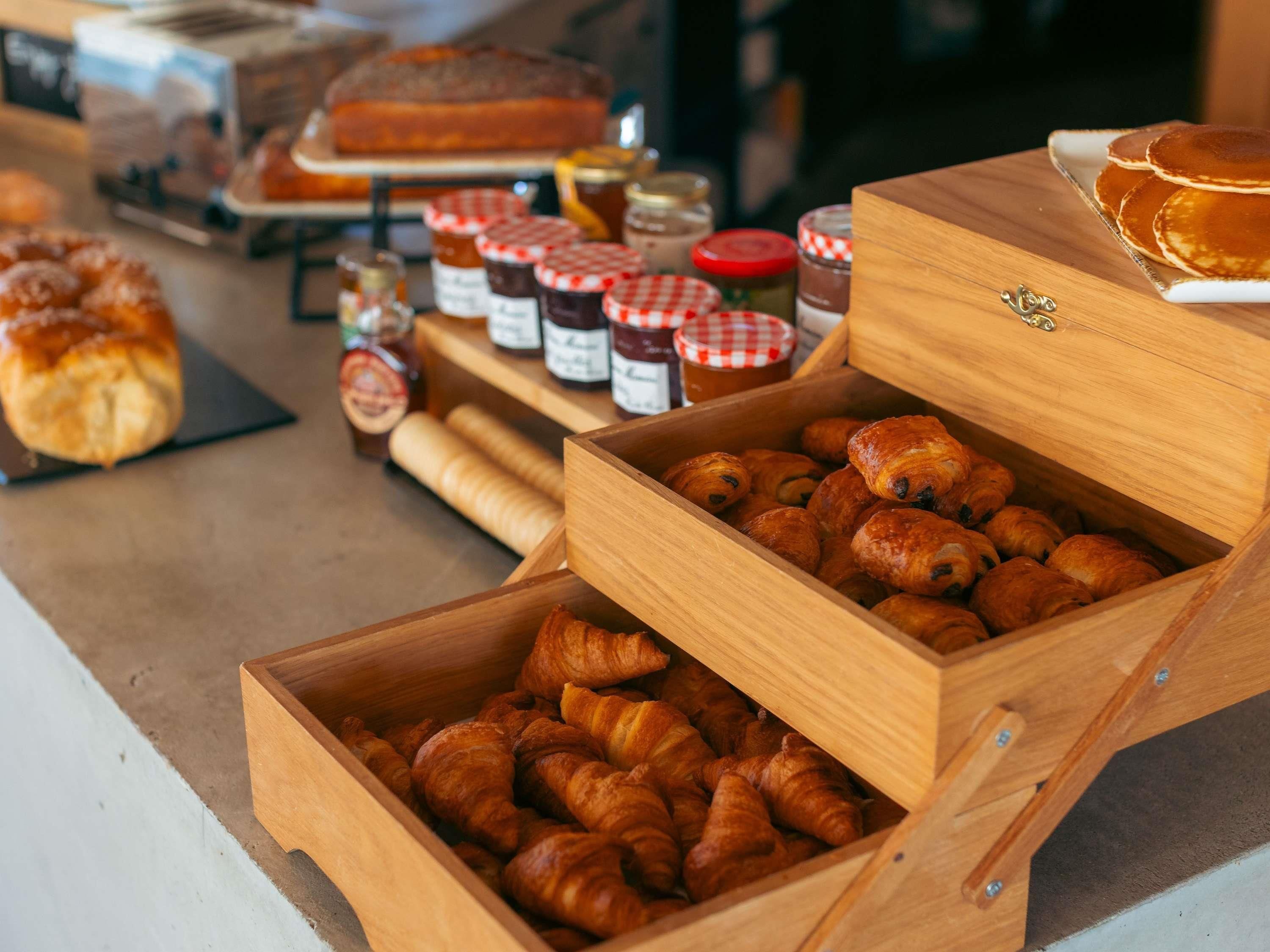 A bakery display with pastries and jars of jam.
