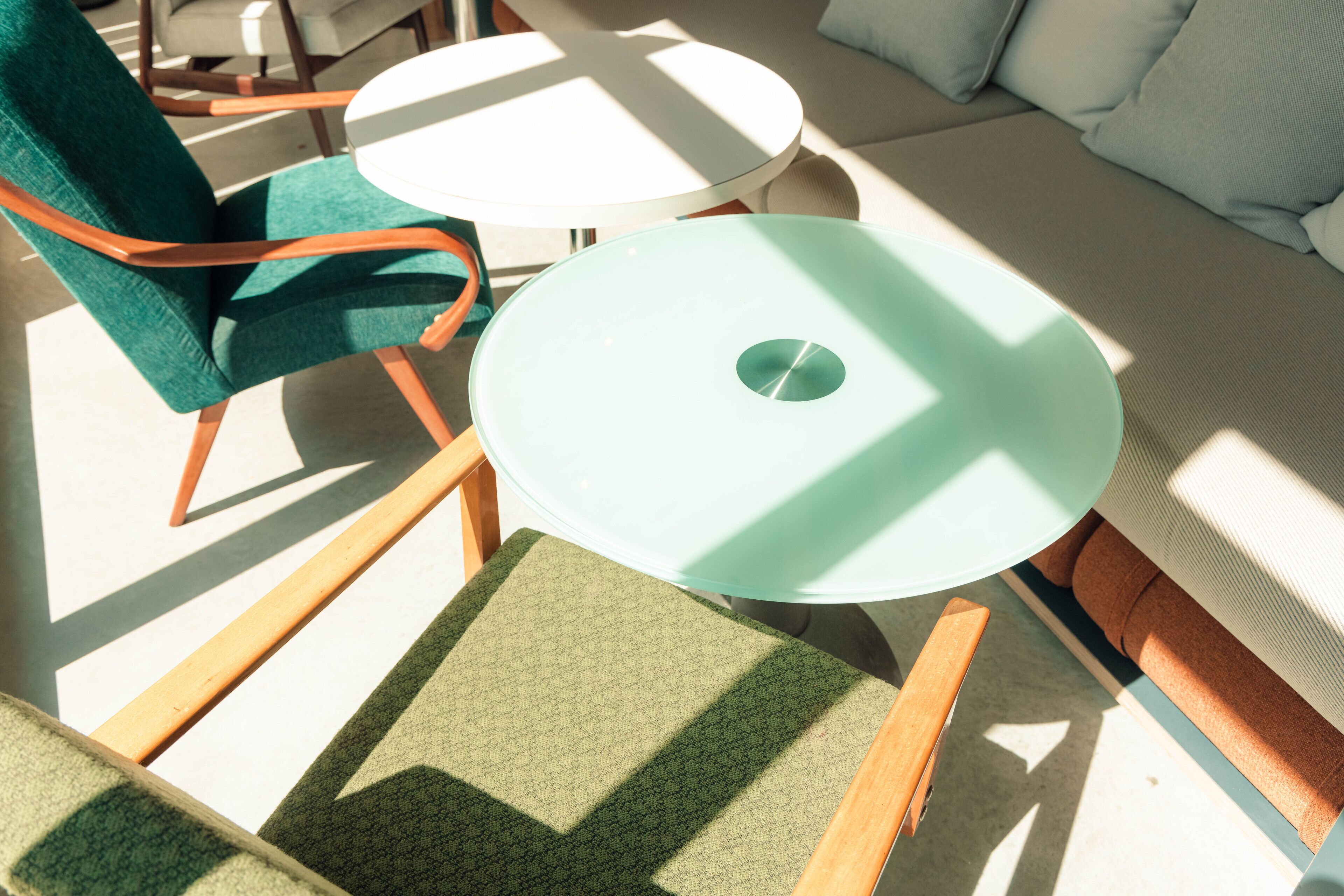 A room with a round table, a green chair, and a sofa.