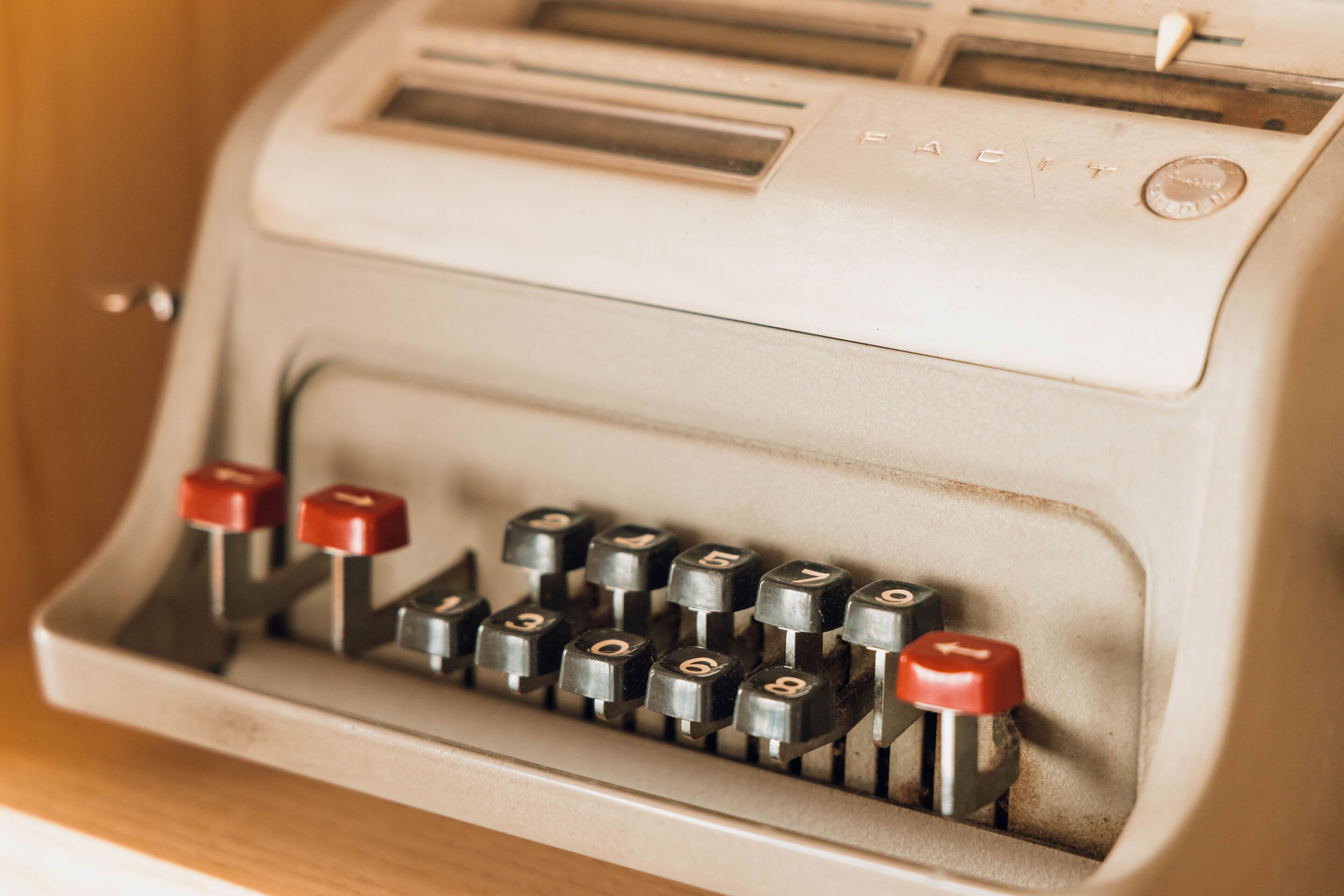 Une machine à écrire ancienne, de couleur beige, avec des touches rouges.