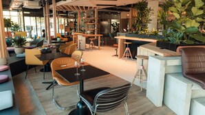 A modern lounge area with seating arrangements, a bar, and various plants. - ibis Styles La Rochelle Centre Gare (La Rochelle)