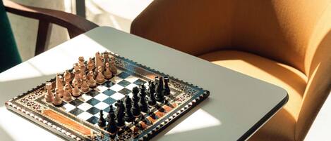 A chessboard on a table with a chair beside it.
