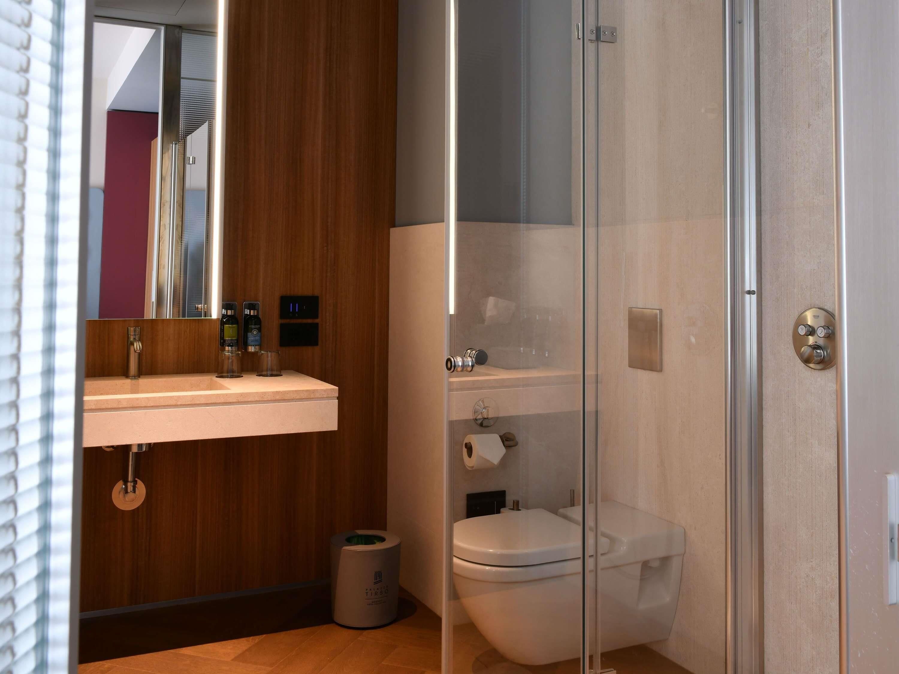 Un baño moderno con tocador de madera, inodoro y cabina de ducha de vidrio.