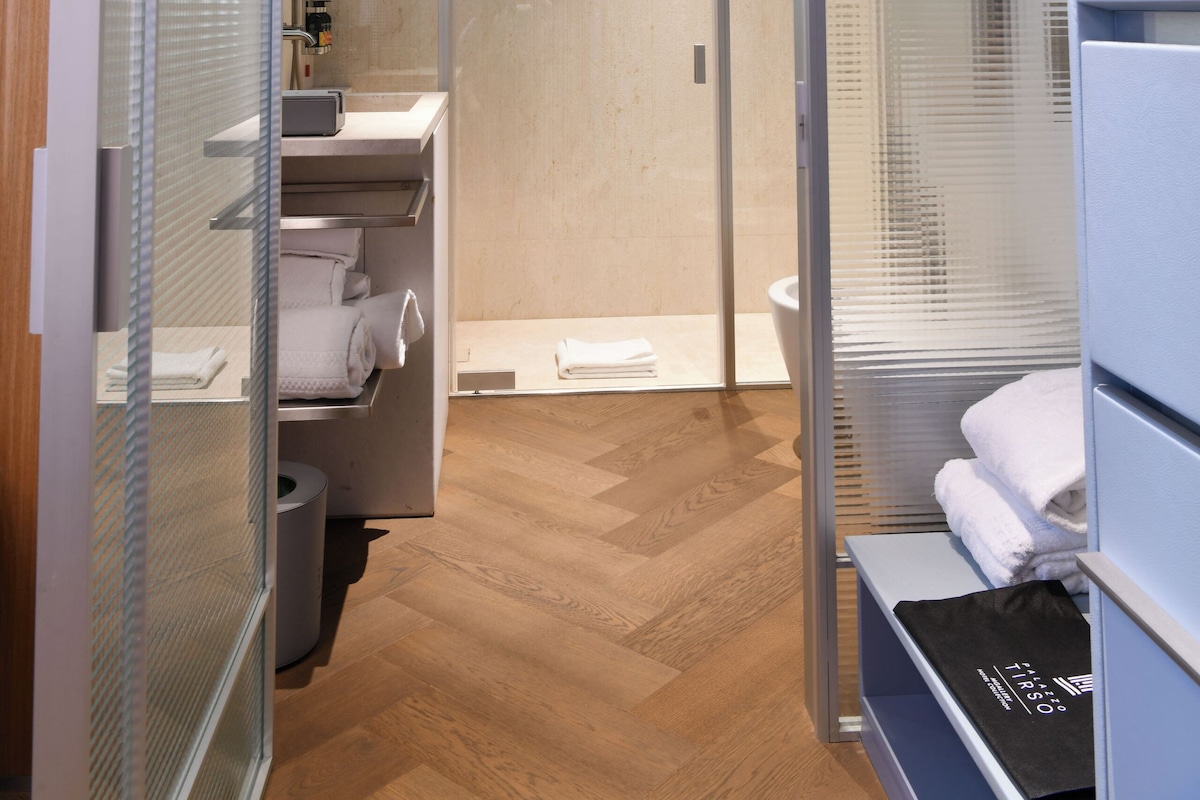 Een moderne badkamer met een douchecabine van glas, een houten vloer en een handdoekhouder.
