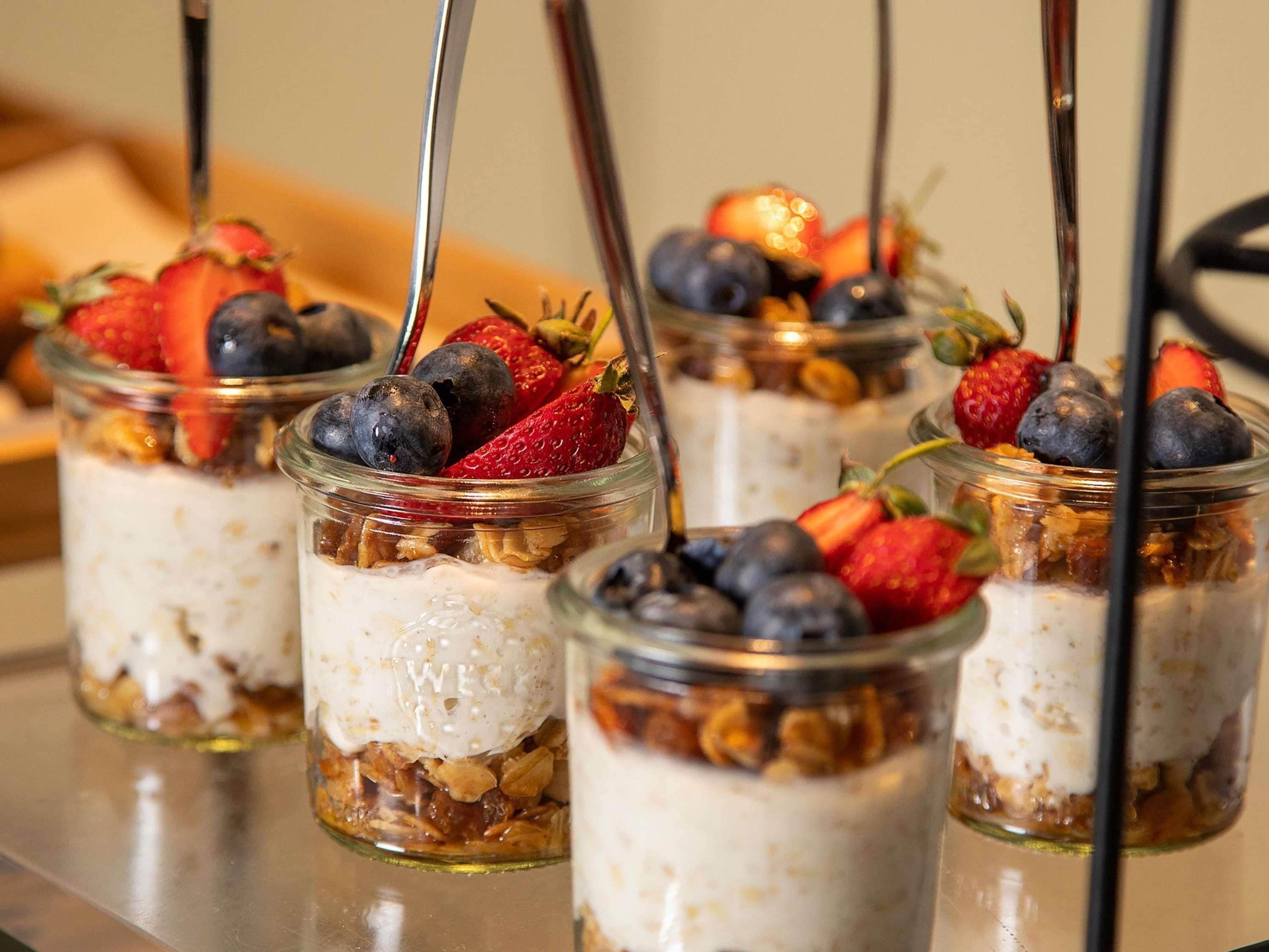 Cuatro tarros de vidrio con capas de ingredientes y frutas por encima.