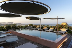 Una piscina al aire libre, sombrillas, sillones reclinables de piscina