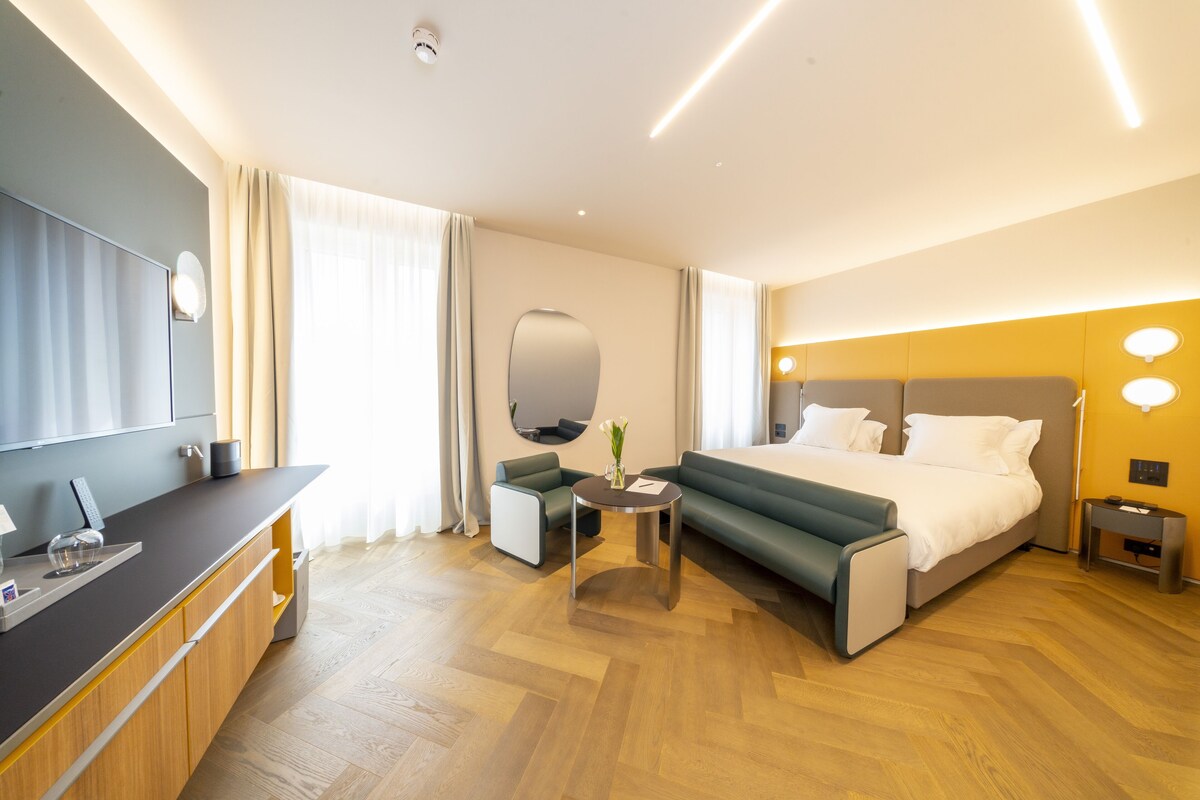 Een moderne hotelkamer met een bed, een bureau, een stoel en een klein tafeltje.