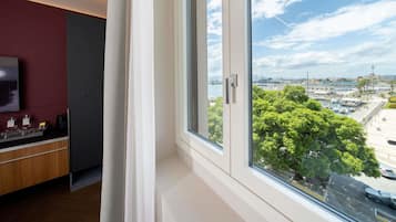 A room with a large window, a TV on the wall, and a view of a marina with boats.