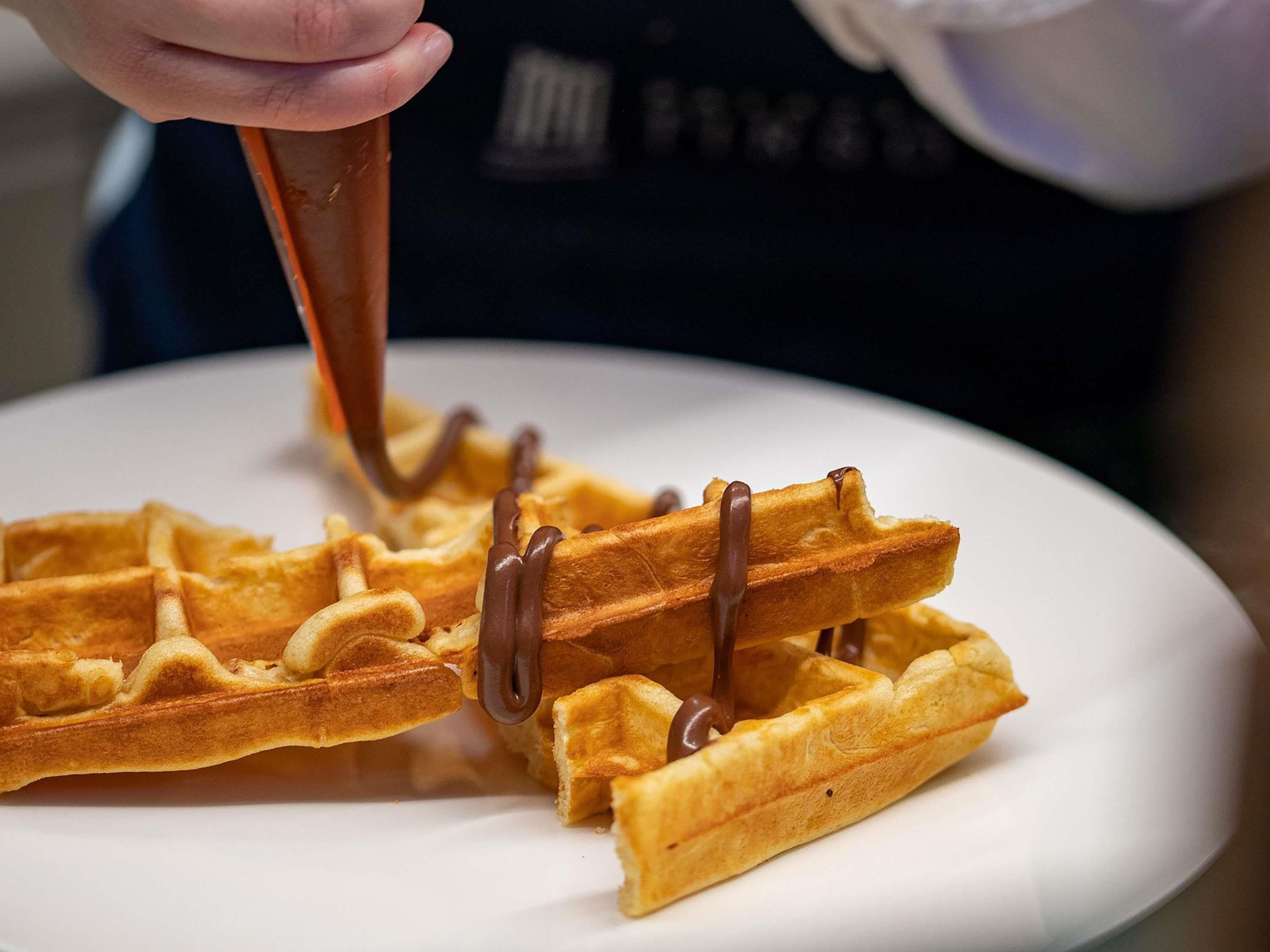 Ein Waffel wird mit Schokoladensauce übergossen.