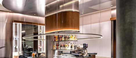 A modern bar area with a central circular bar, a variety of bottles, and a seating arrangement with chairs.