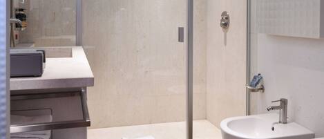 Un baño moderno con ducha acristalada, tocador con lavabo y un espejo grande.