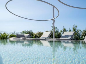 A clear swimming pool with lounge chairs and a metal structure overhead. - Palazzo Tirso Cagliari Mgallery (Cagliari)