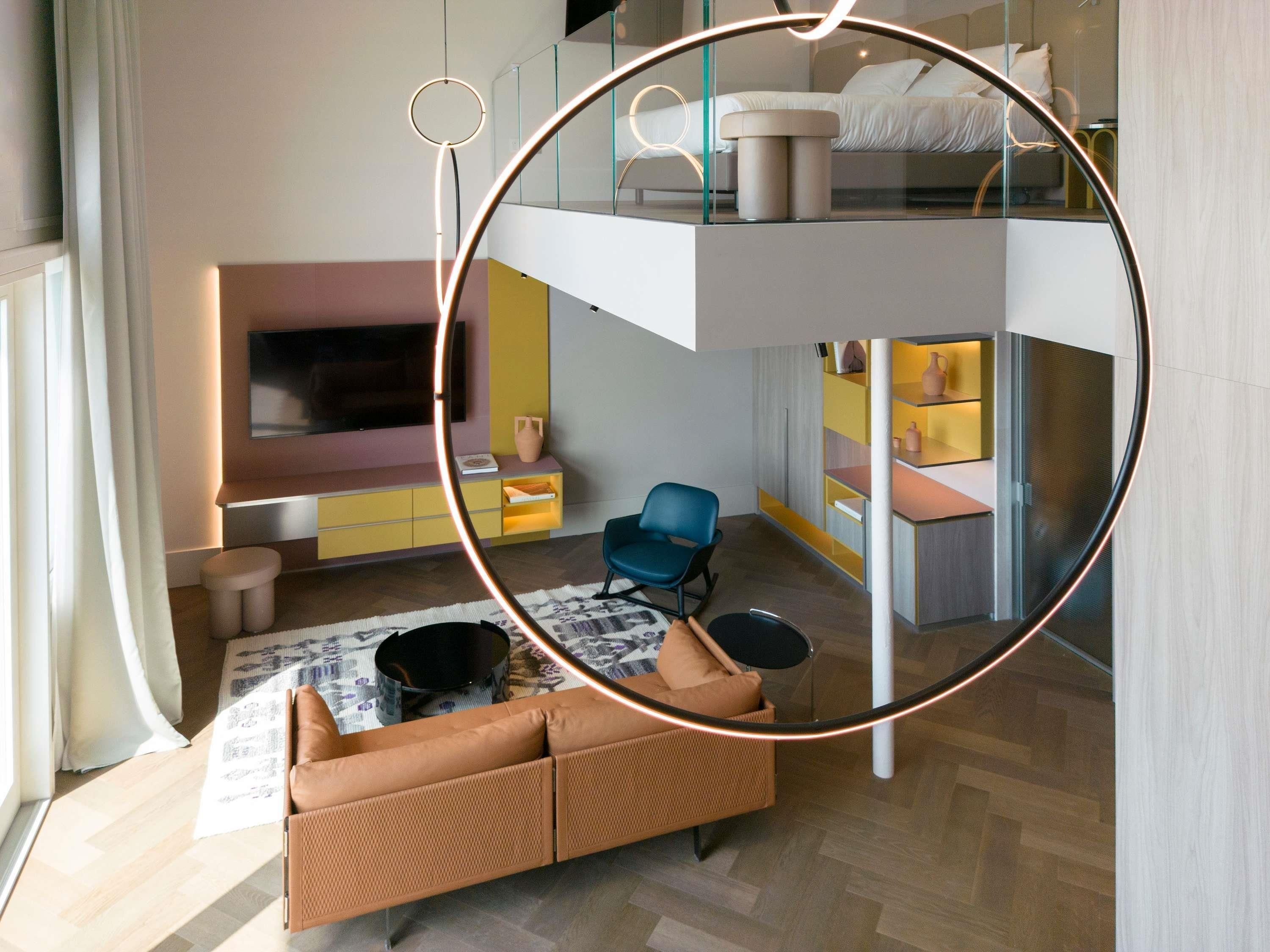 A modern interior with a sofa, a chair, a TV, and a kitchen area.