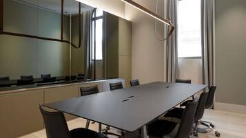 A conference room with a long table, black chairs, and a modern ceiling light fixture.