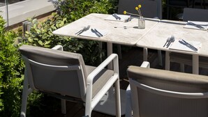 Un espace extérieur aménagé pour prendre les repas, avec une table et des chaises, offrant une vue sur le paysage urbain.