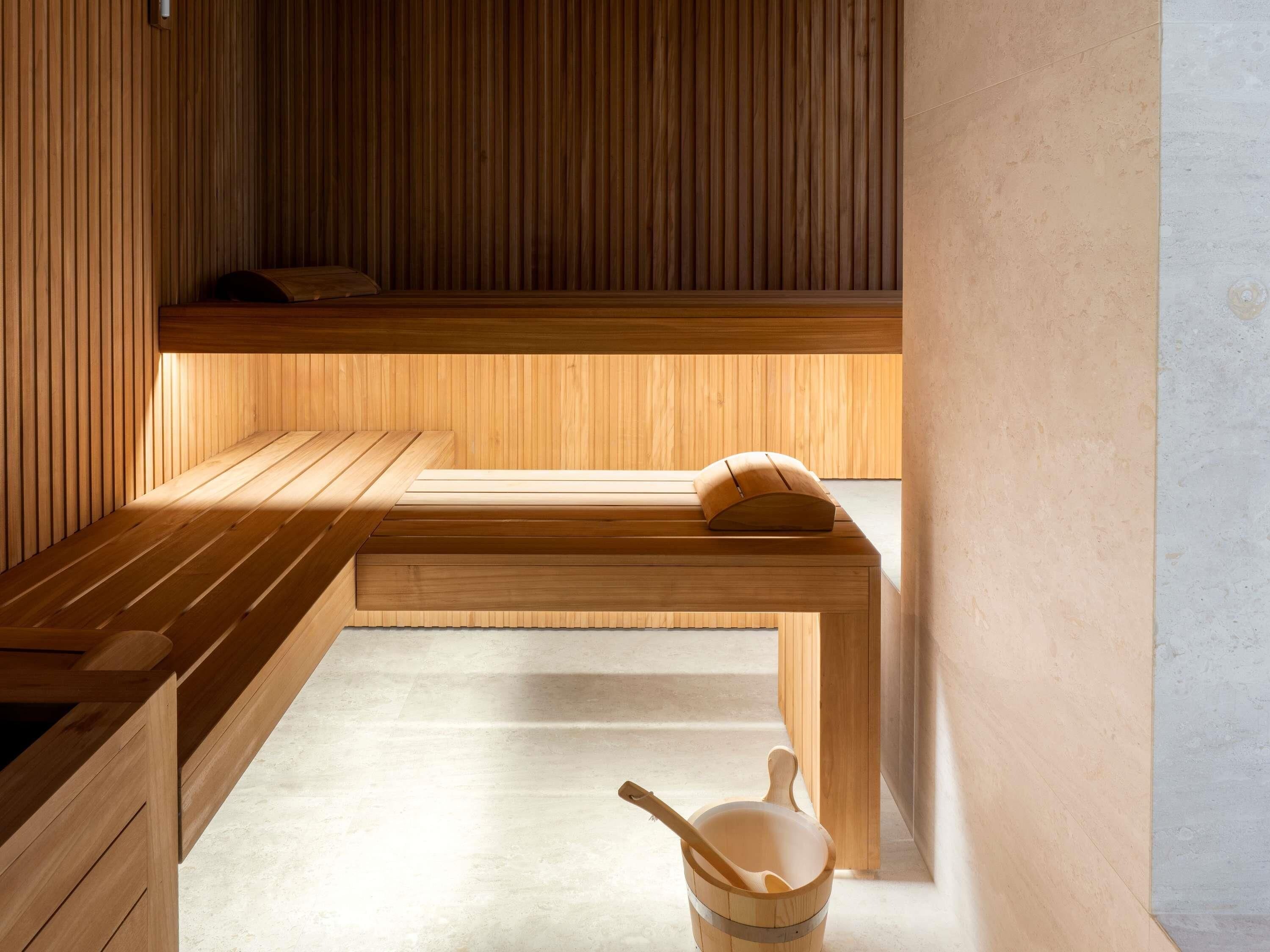 A wooden sauna with benches and a wooden bucket.