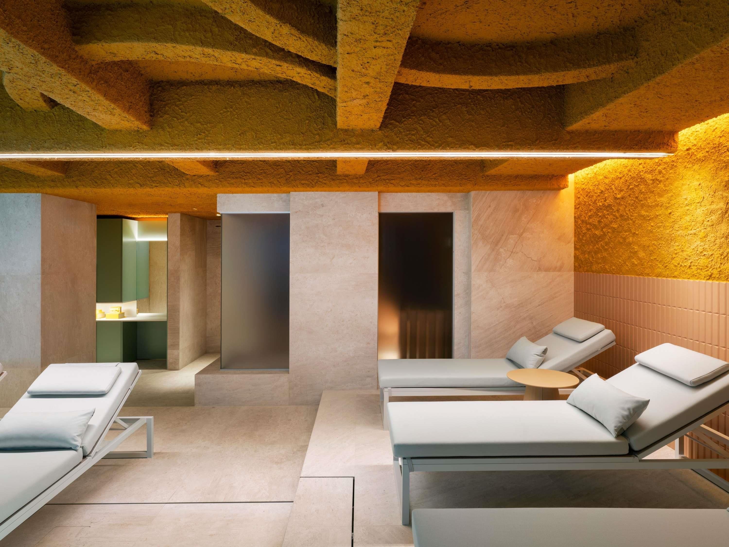 A spa room with three reclining chairs, a massage table, and a small table with a lamp.