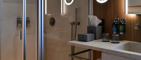 A modern bathroom with a glass shower enclosure, a vanity with a mirror, and toiletries.
