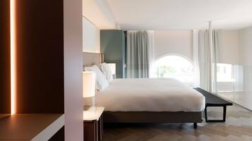 Een moderne hotelkamer met een groot bed, nachtkastjes, een bureau en uitzicht op de omgeving.