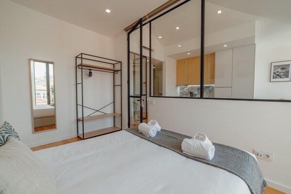 Habitación de hotel con una cama grande, armario empotrado, espejo y vistas a la ciudad desde la ventana.