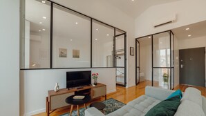 A modern living room with a large TV, a sofa, and a small table. - Courtyard Oporto Design Apartment G (Porto)