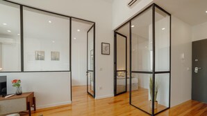 A modern interior with wooden flooring, a sofa, a coffee table, and a TV. There are framed pictures on the wall and a door with a handle. - Courtyard Oporto Design Apartment G (Porto)