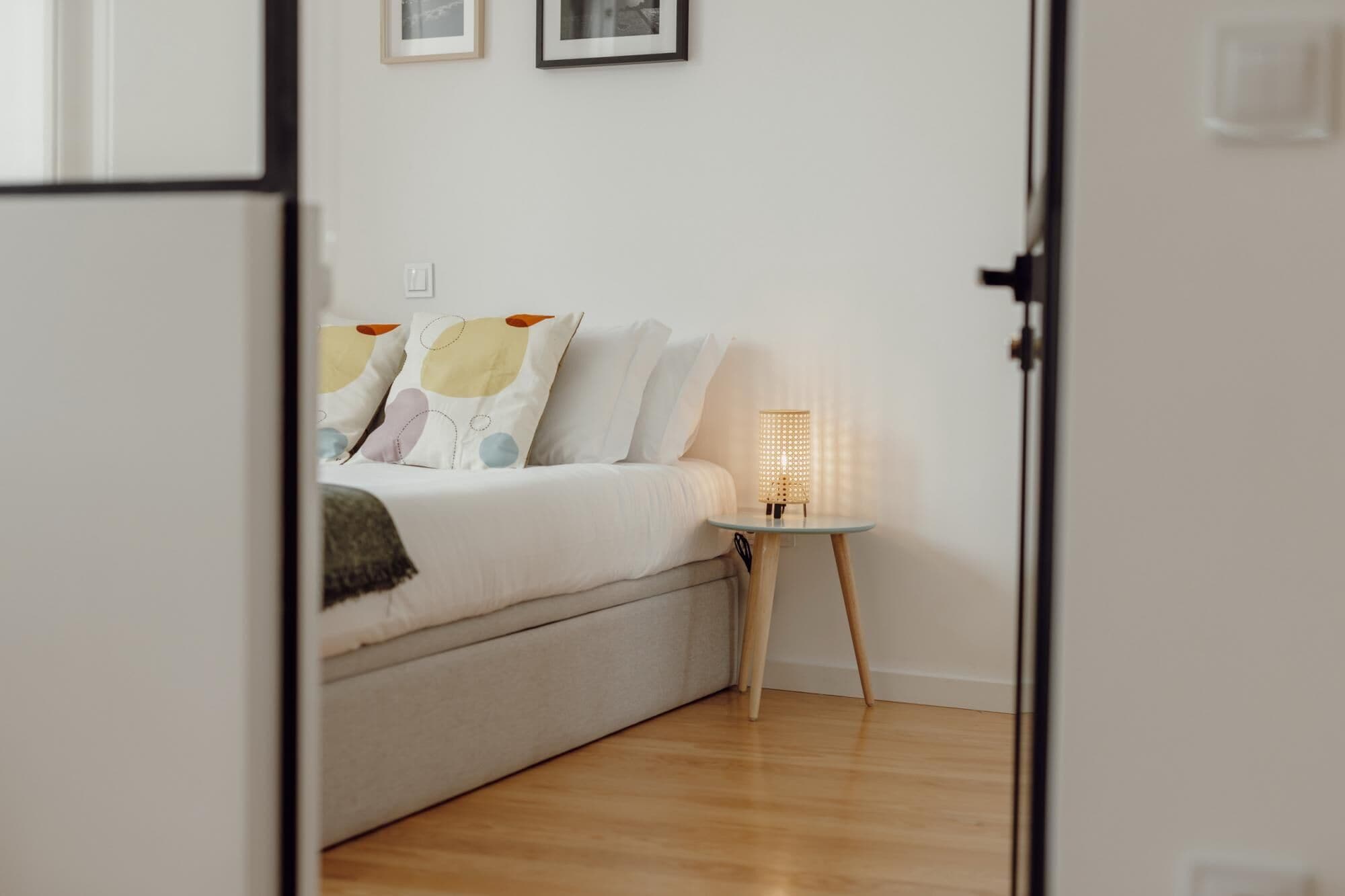 Ein Schlafzimmer mit einem Bett, einem Nachttisch mit Lampe und einem an der Wand befestigten Lichtschalter.