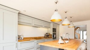 Une cuisine moderne avec des armoires blanches, un plan de travail en bois et des luminaires suspendus.