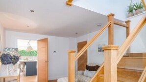 Un intérieur moderne avec un escalier en bois, un coin cuisine et un espace salon offrant une vue agréable.