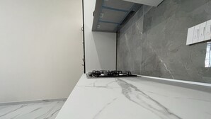 Une cuisine moderne dotée d’un plan de travail en marbre, d’une cuisinière à gaz et d’un dosseret de carrelage gris.