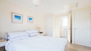 Ein Schlafzimmer mit einem großen Bett, einem Nachttisch mit Lampe und einer Tür zu einem Badezimmer.