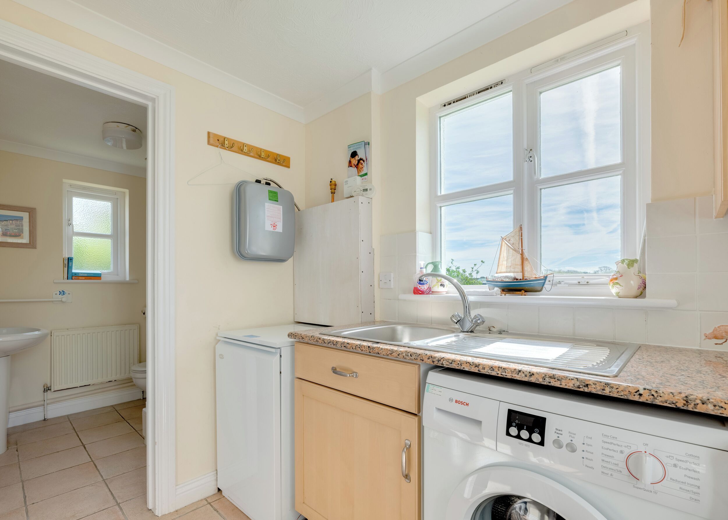 A compact kitchen with a built-in washing machine, a window with a view, and a small window sill with decorative items.