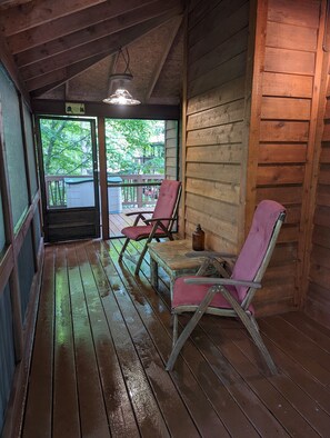 Eine Holzjagdhaus mit Veranda, zwei Schaukelstühlen und einem Tisch.