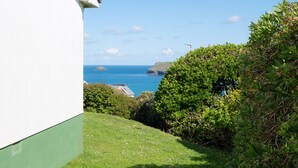 A coastal view with a white building, a grassy area, and dense foliage.