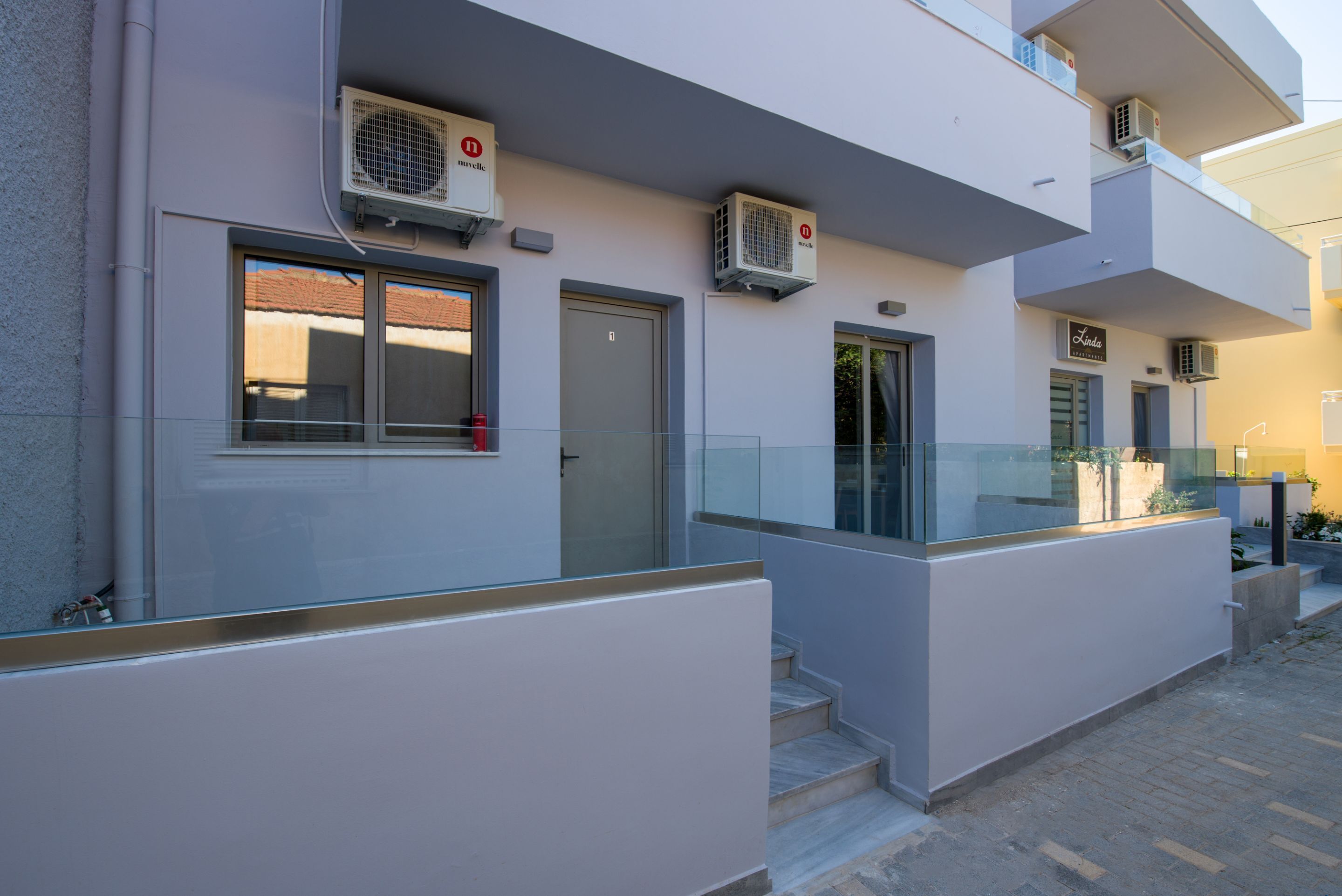 A modern building with air conditioning units, a glass balcony, and a fire extinguisher.