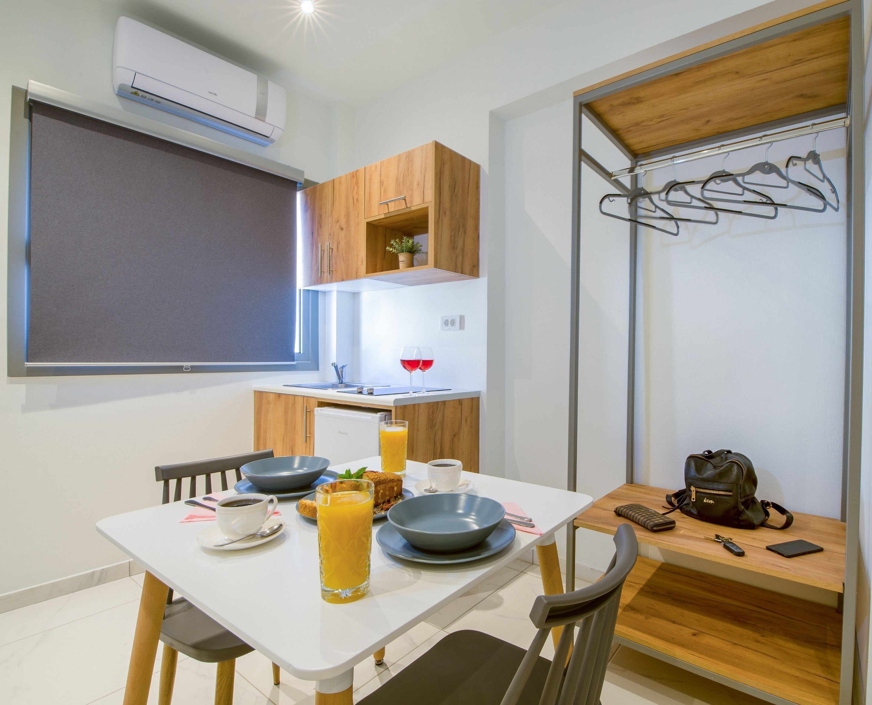 A compact kitchen with a dining table set for breakfast, including a glass of orange juice, a bowl of cereal, and a cup of coffee.