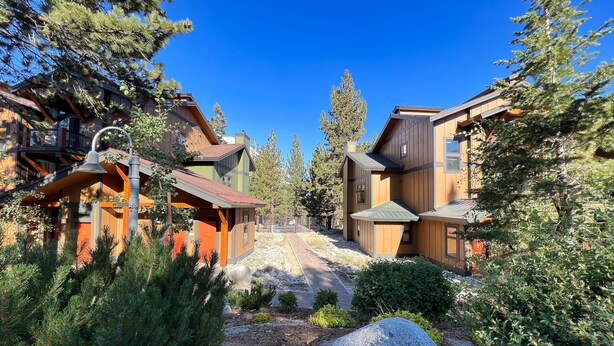 A modern lodge with a central courtyard, surrounded by wooden buildings and dense forest. - Solstice #14 2 Bedroom Condo by RedAwning (Mammoth Lakes)