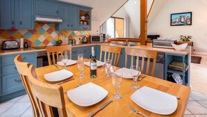 Eine moderne Küche mit blauen Schränken, einem Holzespeisesaal für sechs Personen und einer farbenfrohen Spritzschutzwand.