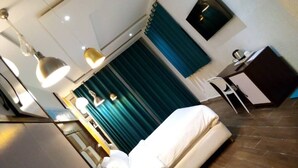 Quarto de hotel com cama, escrivaninha e duas luminárias pendentes.