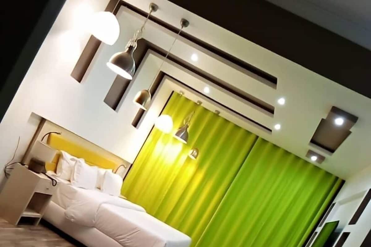 Een moderne hotelkamer met een bed, nachtkastje en een bureau met stoel.
