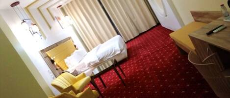 Una habitación de hotel con cama, escritorio, silla y alfombra roja.