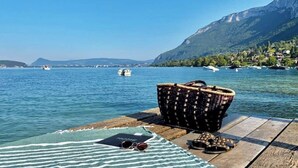 A wooden dock with a woven basket, a towel, and a pair of sunglasses on a wooden table.