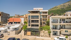 Un edificio de varios pisos con balcones, fachada de piedra y vistas a una ladera.