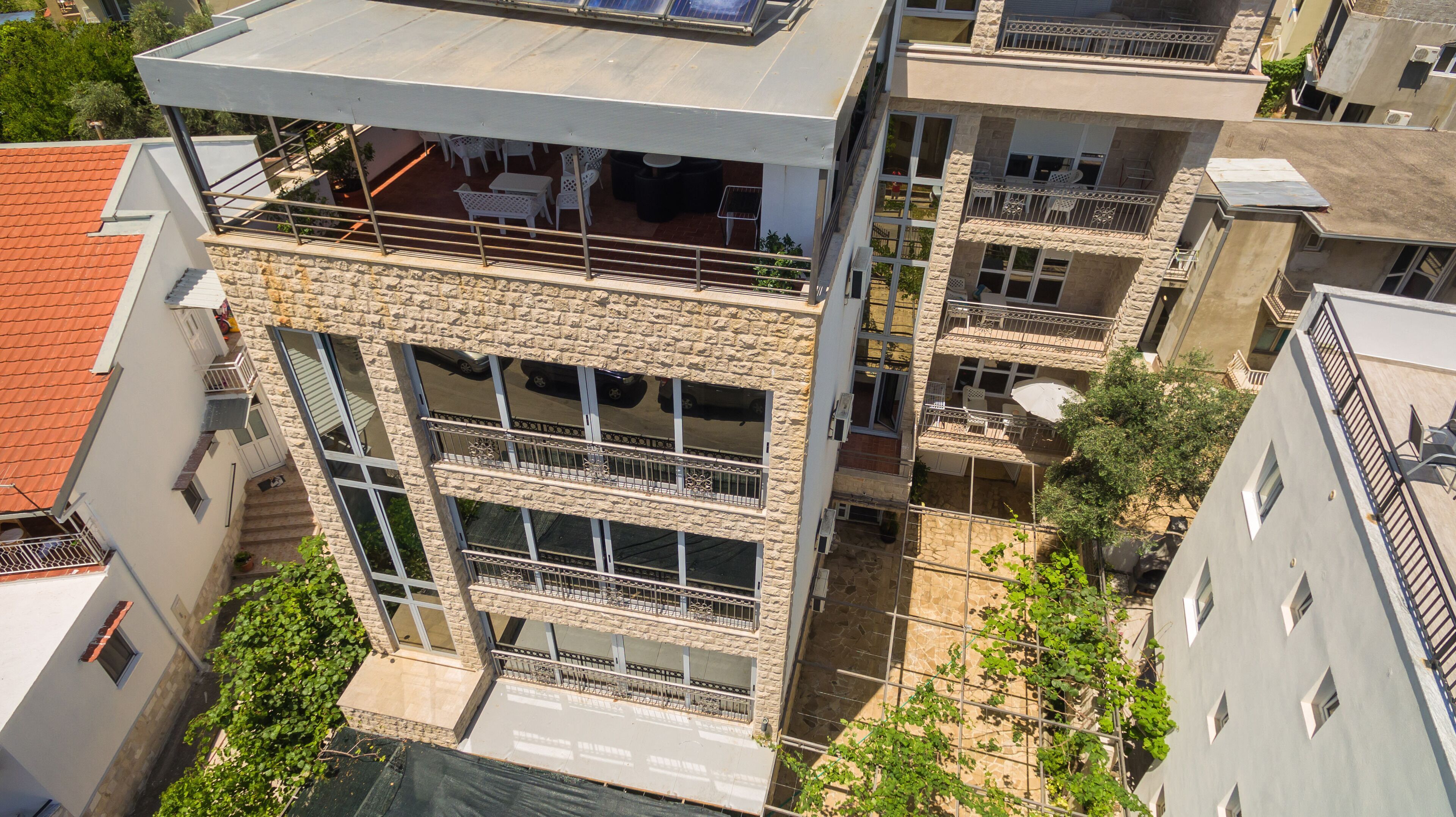 A multi-story building with balconies, large windows, and a rooftop terrace.