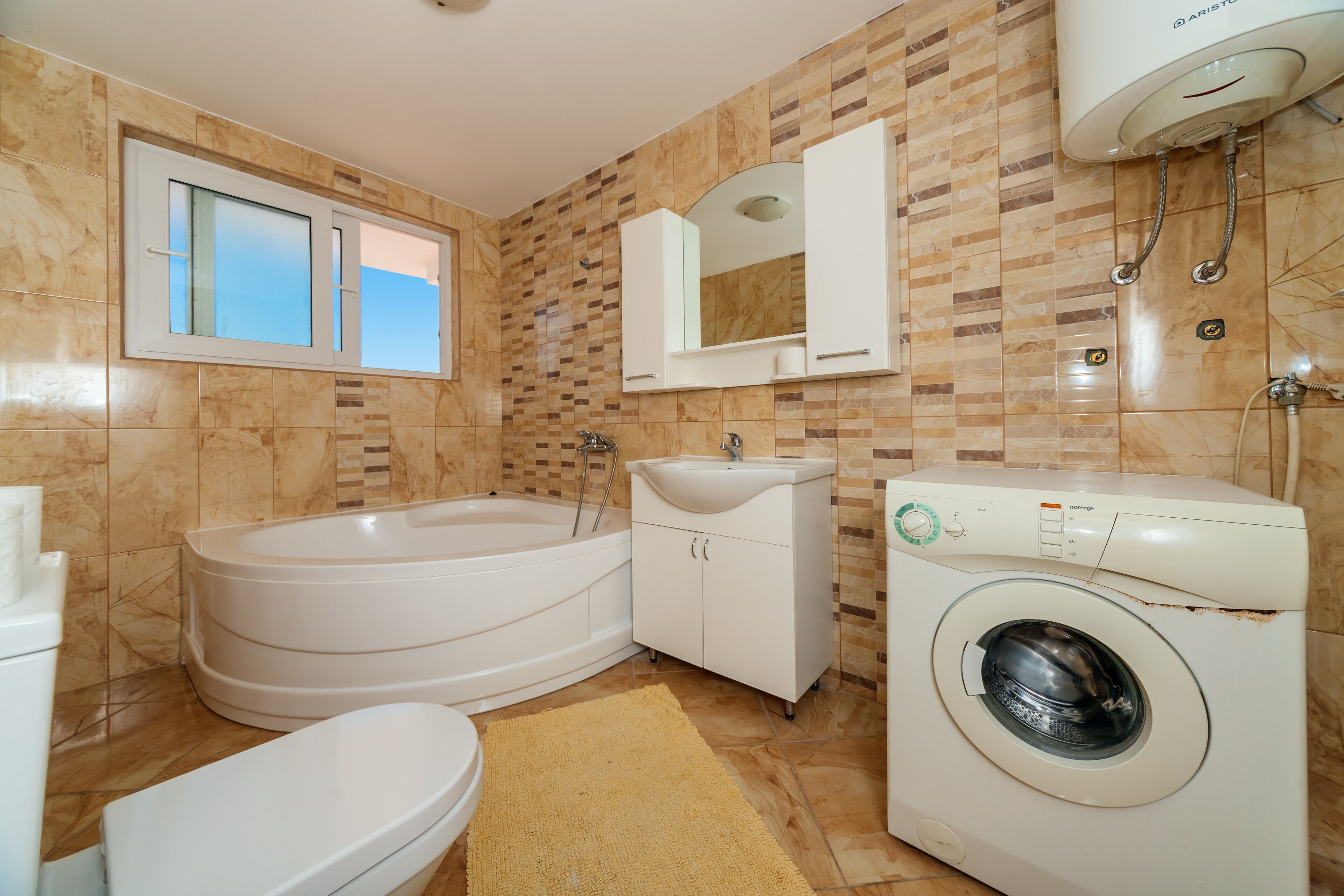 Une salle de bain équipée d’une baignoire, de toilettes, d’un lavabo et d’un lave-linge.