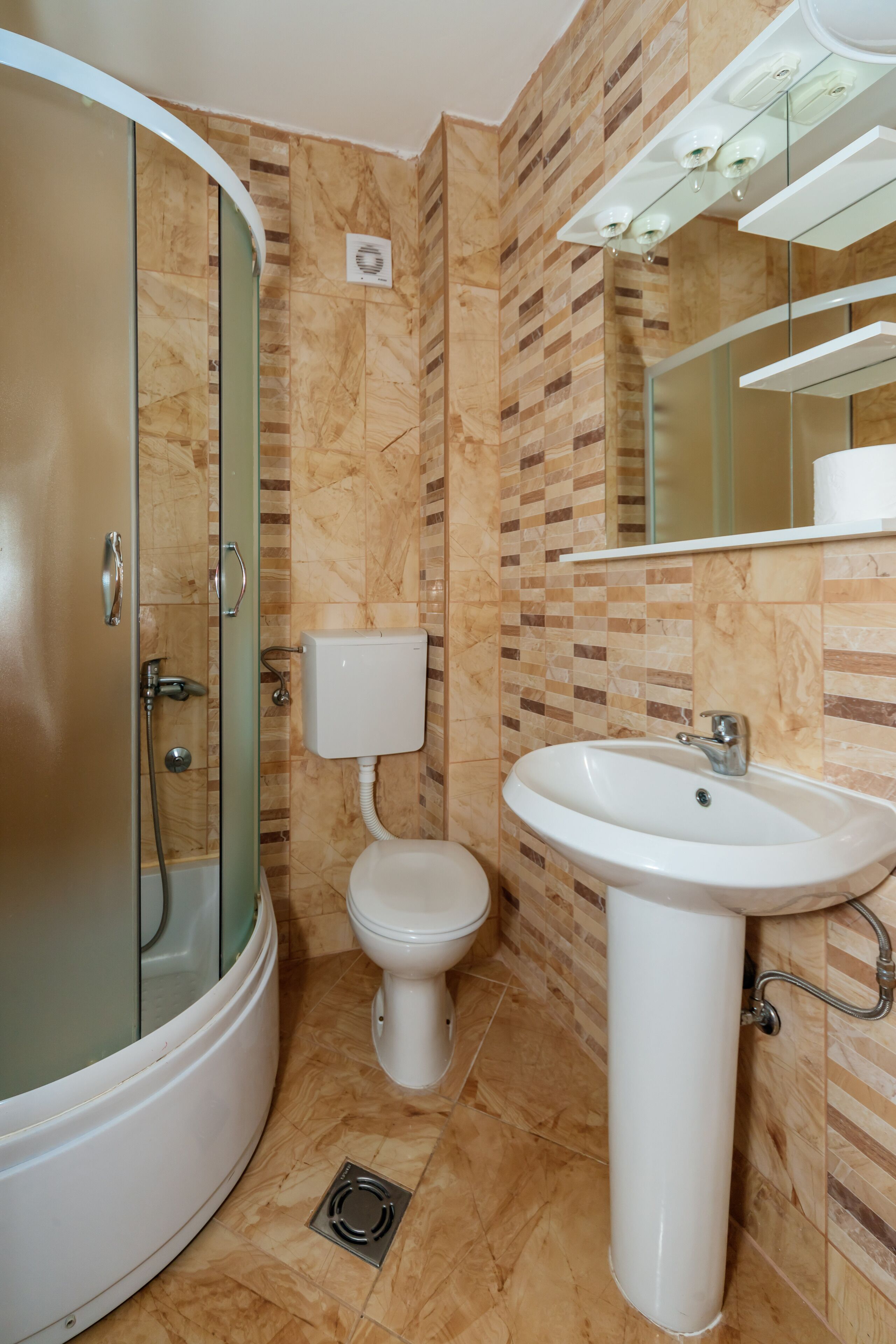 Un baño con ducha de mampara de vidrio, inodoro y lavamanos.