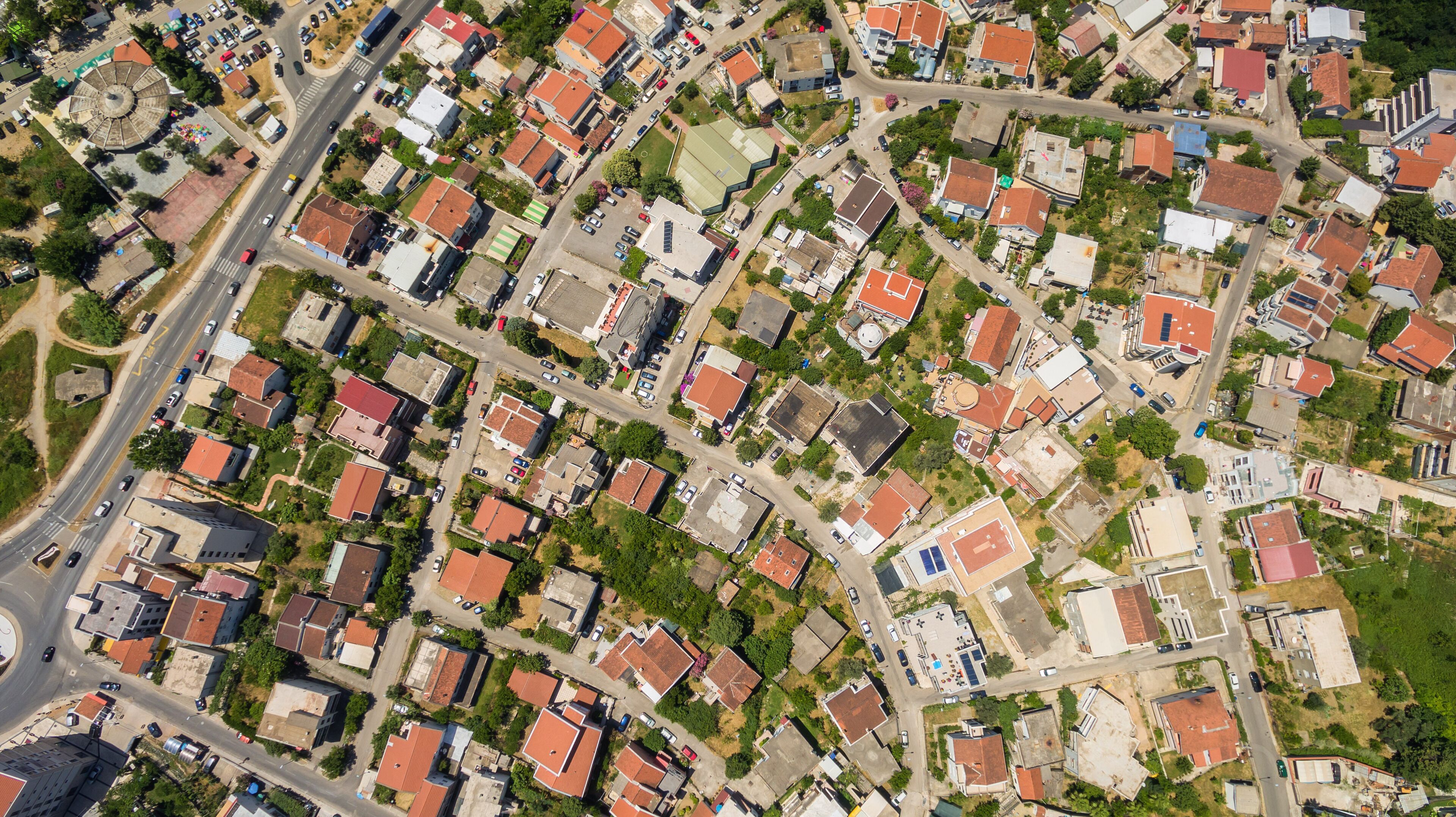 An aerial view of a residential area with streets, houses, and a central roundabout.