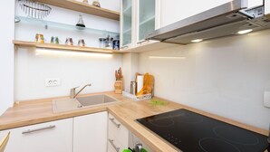 A compact kitchen with a built-in stove, a sink, and a small countertop. There are shelves above the sink and a window above the stove. - Apartment Jadranka with Sea View in Rogotin (Rogotin)