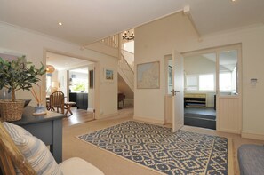 A spacious living area with a staircase, a dining table, and a large rug.