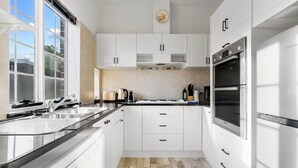 Una cocina moderna con armarios blancos, horno de acero inoxidable y un amplio ventanal que proporciona luz natural.