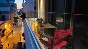 A balcony with a red chair, a small table, and a potted plant.